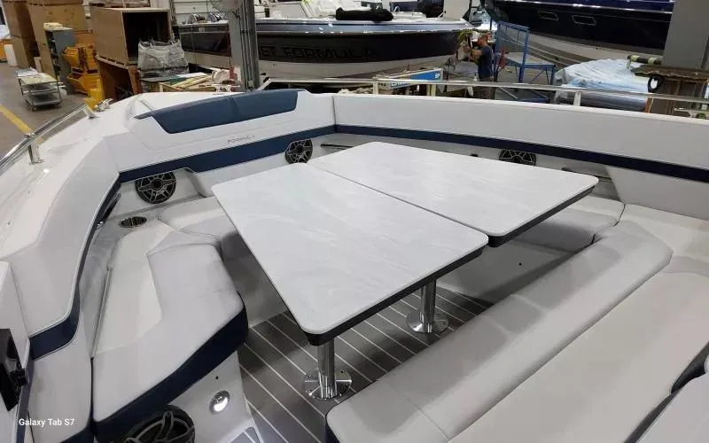 Slide: The Image of 2025 Formula 400 Super Sport Crossover boat interior with seating and table in a showroom. - 22