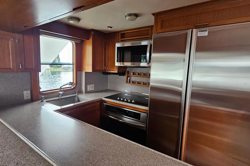 Slide: The Image of 1987 DeFever 53 POC yacht kitchen with wood cabinetry, stainless steel appliances, and large windows. - 40