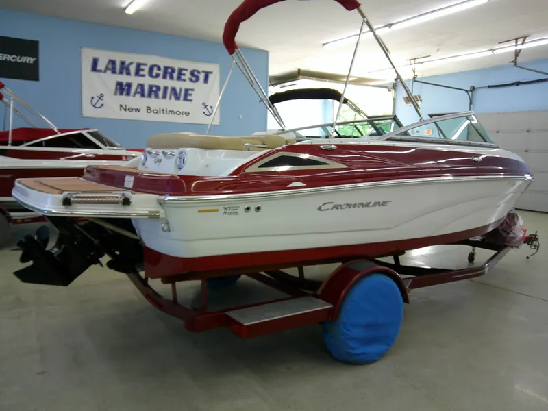 Slide: The Image of 2018 Crownline 205 SS boat in showroom, red and white design, on trailer. - 1