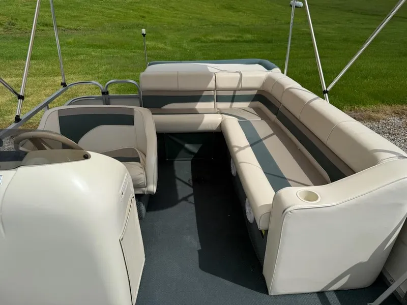 Slide: The Image of Pontoon boat interior with beige seating, Playbuoy PB Calypso SE 2023 model, grassy background. - 11