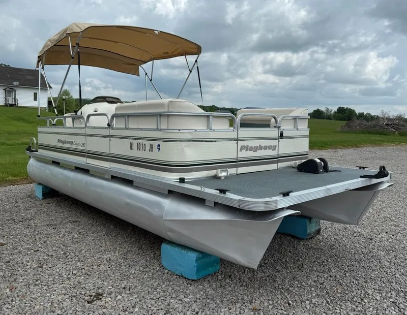 Slide: The Image of Pontoon boat Playbuoy PB Calypso SE 2023, 2001 model, parked on gravel with canopy. - 2