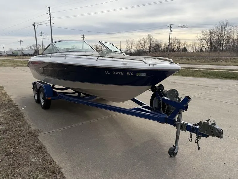Slide: The Image of 1996 Sea Ray 210 Signature boat on trailer, parked on concrete, overcast sky. - 3