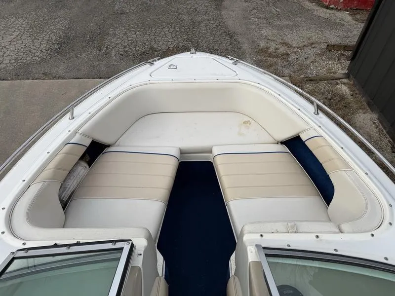 Slide: The Image of 1996 Sea Ray 210 Signature boat with white and beige seating, docked on a textured surface. - 9