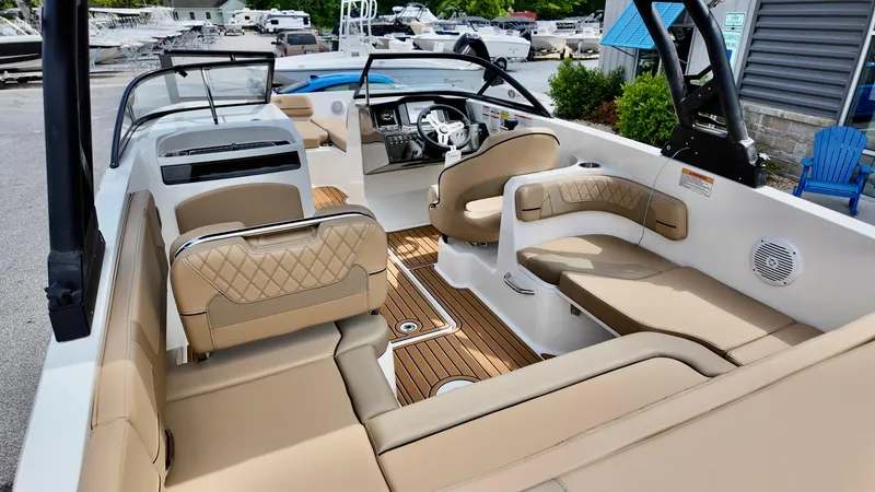 Slide: The Image of 2025 Bayliner VR6 boat interior with beige seating and wood accents, docked at a marina. - 10