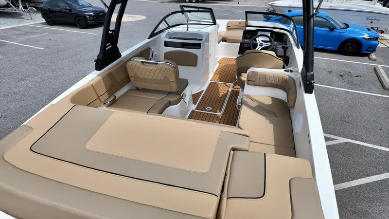 Slide: The Image of 2025 Bayliner VR6 boat interior with beige seating and sleek design in a parking lot. - 13