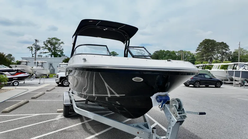 Slide: The Image of 2025 Bayliner VR6 boat on trailer in parking lot, black hull, canopy top. - 14