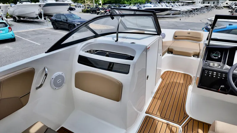 Slide: The Image of 2025 Bayliner VR6 boat interior with sleek design and wood accents in a marina setting. - 6