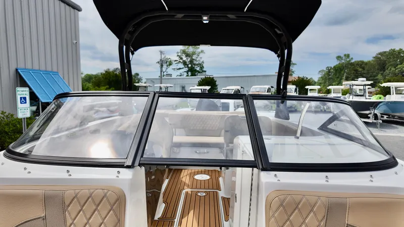 Slide: The Image of 2025 Bayliner VR6 boat interior with tan seating and wood flooring, docked outdoors. - 8