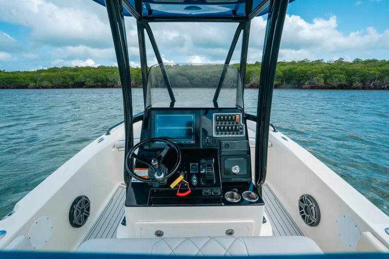 Slide: The Image of 2015 Hydra-Sports 23 Bay boat dashboard with steering wheel and controls on calm water. - 2