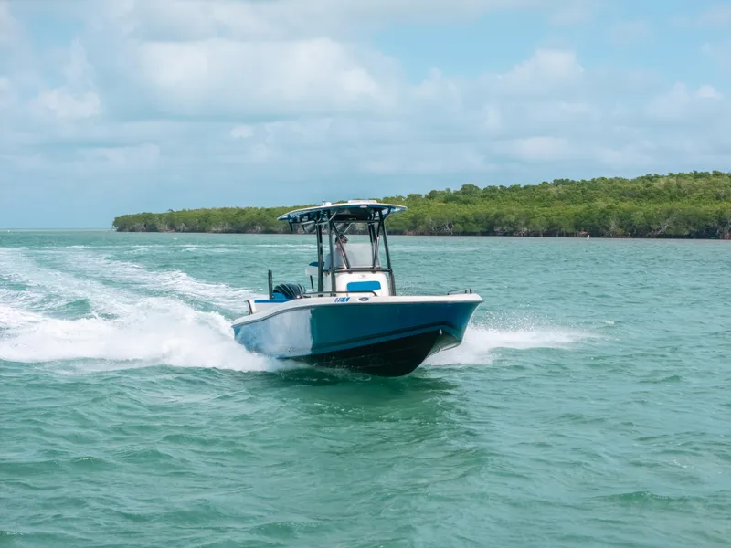 Slide: The Image of 2015 Hydra-Sports 23 Bay boat cruising on turquoise water near lush green shoreline. - 28