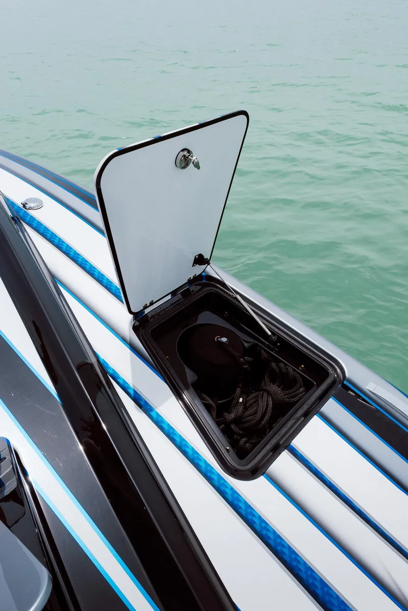Slide: The Image of 2024 MTI 440X boat with open storage compartment on deck, near calm water. - 49