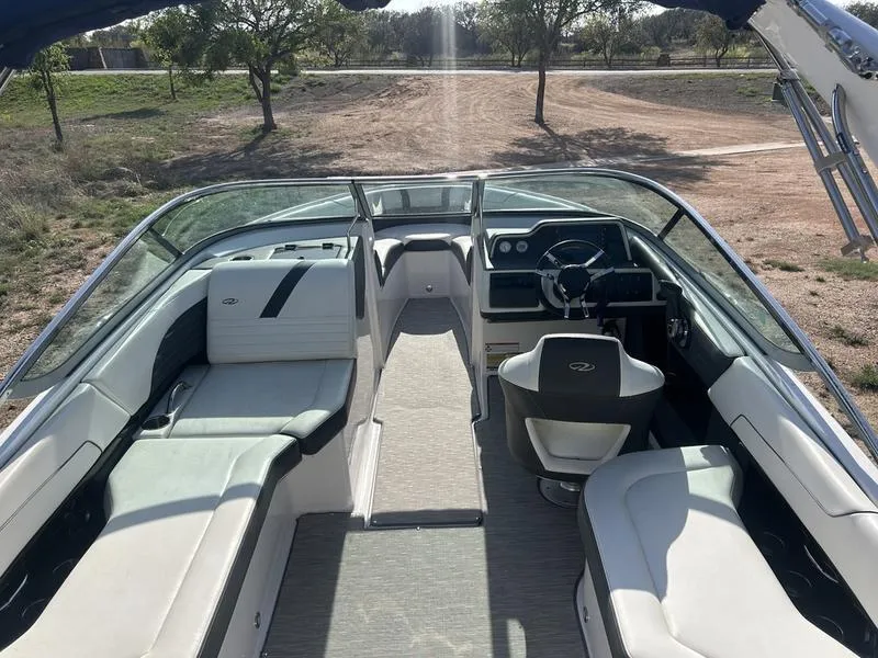 Slide: The Image of 2017 Regal 2300 Bowrider interior with seating and steering, parked on a dirt path. - 3