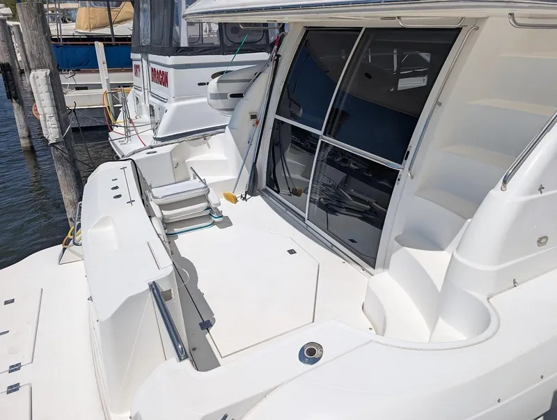 Slide: The Image of 2003 Cruisers Yachts 5000 Sport Sedan docked, featuring spacious deck and sleek design. - 13