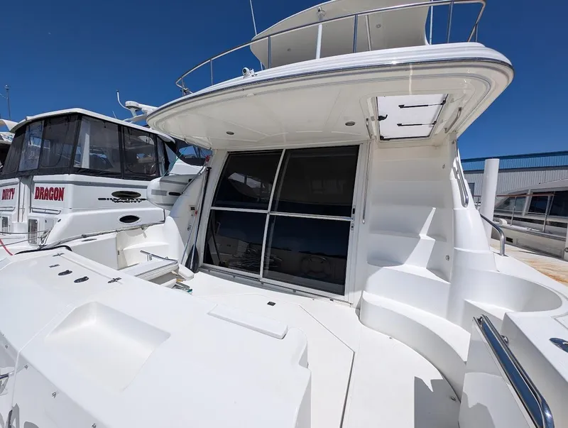 Slide: The Image of 2003 Cruisers Yachts 5000 Sport Sedan docked, showcasing sleek design and spacious deck. - 14