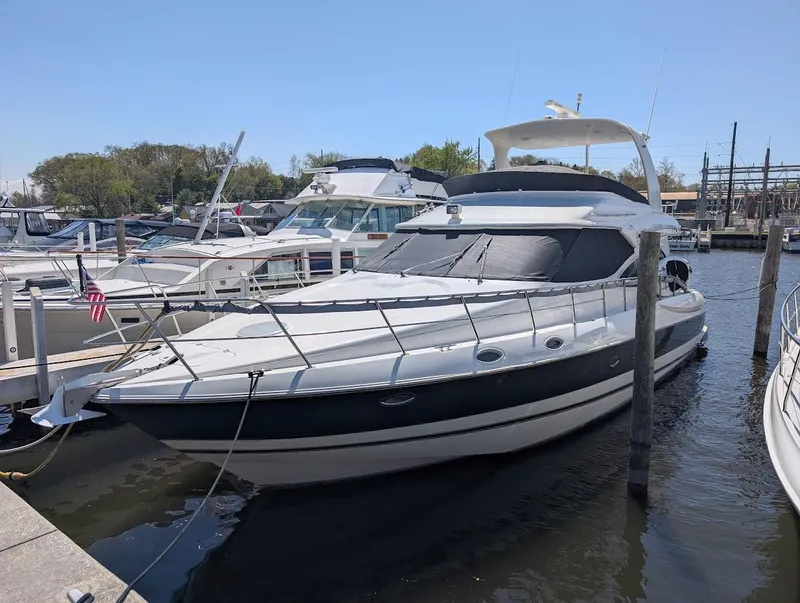 Slide: The Image of 2003 Cruisers Yachts 5000 Sport Sedan docked at marina under clear sky. - 2