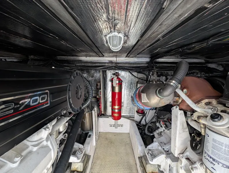 Slide: The Image of Engine room of 2003 Cruisers Yachts 5000 Sport Sedan with visible machinery and fire extinguisher. - 23