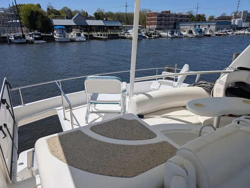 Slide: The Image of 2003 Cruisers Yachts 5000 Sport Sedan on a marina, featuring spacious deck seating. - 41