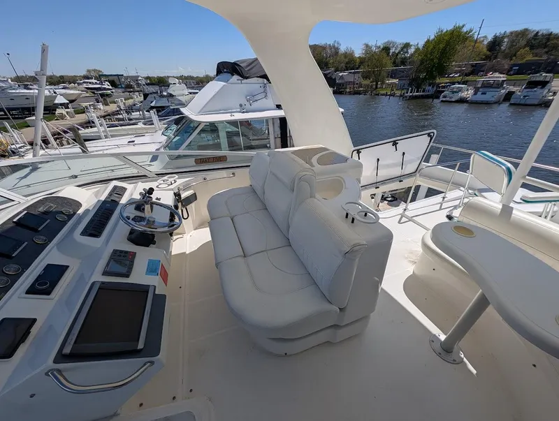 Slide: The Image of 2003 Cruisers Yachts 5000 Sport Sedan helm with plush seating and marina view. - 43