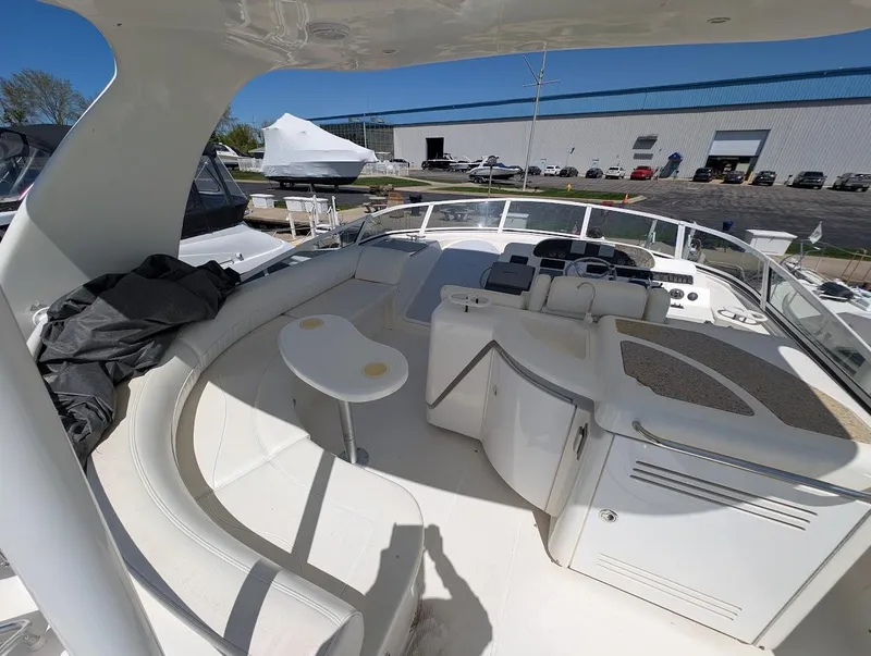 Slide: The Image of 2003 Cruisers Yachts 5000 Sport Sedan, spacious deck with seating and table, marina background. - 44