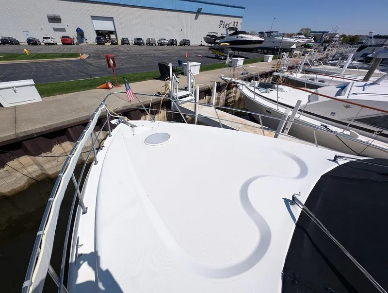 Slide: The Image of 2003 Cruisers Yachts 5000 Sport Sedan docked at marina, showcasing spacious deck. - 7