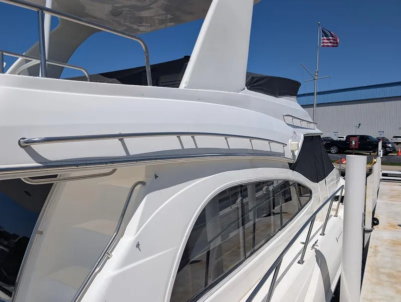 Slide: The Image of 2003 Cruisers Yachts 5000 Sport Sedan docked, showcasing sleek design and American flag in background. - 8