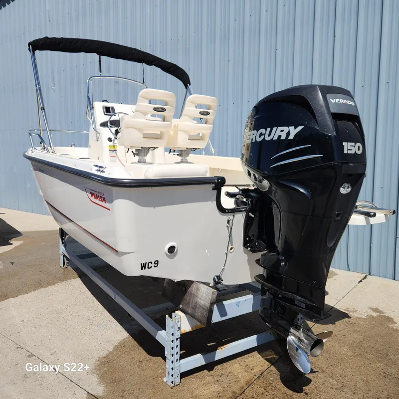 Slide: The Image of 2010 Boston Whaler 190 Outrage boat with Mercury 150 engine, docked outdoors. - 5