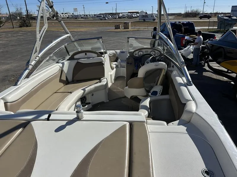 Slide: The Image of 2007 Tigé 22Ve boat interior with beige seating and steering wheel, parked outdoors. - 1