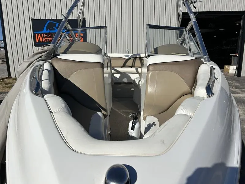 Slide: The Image of 2007 Tigé 22Ve boat interior with beige and white seating, parked near a warehouse. - 3