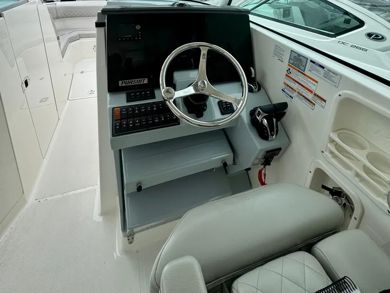 Slide: The Image of 2024 Pursuit DC 295 Dual Console boat helm with steering wheel and controls. - 10