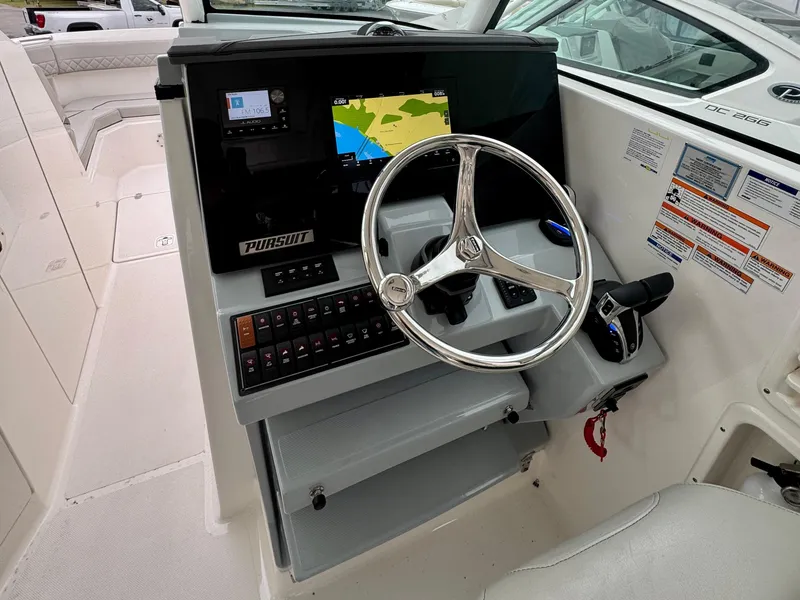 Slide: The Image of 2024 Pursuit DC 295 Dual Console boat helm with steering wheel and navigation display. - 19