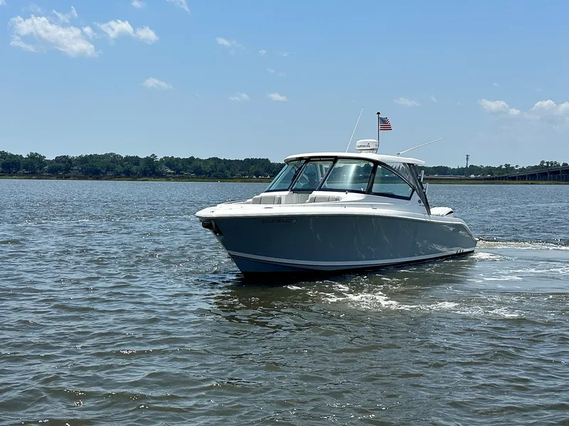 Slide: The Image of 2024 Pursuit DC 295 Dual Console boat cruising on a sunny day. - 2