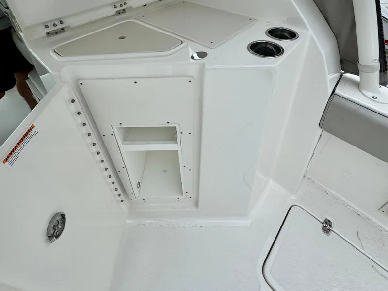 Slide: The Image of 2024 Pursuit DC 295 Dual Console interior with storage compartment and cup holders. - 23