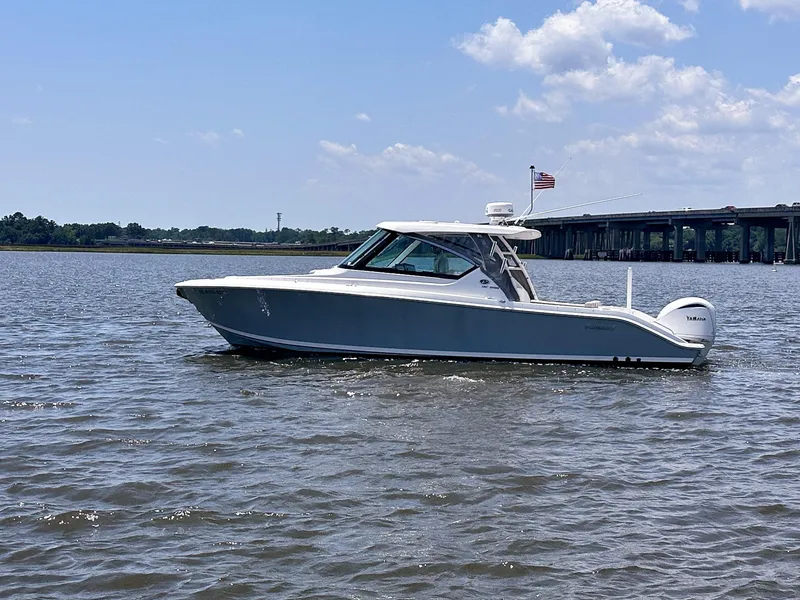 Slide: The Image of 2024 Pursuit DC 295 Dual Console boat cruising on a sunny day near a bridge. - 4