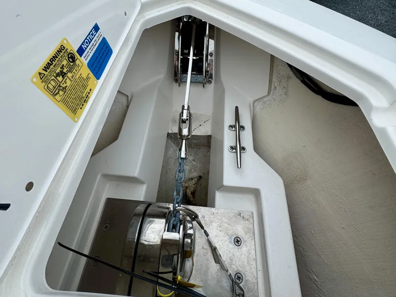 Slide: The Image of 2024 Pursuit DC 295 Dual Console anchor compartment with winch and warning labels. - 9