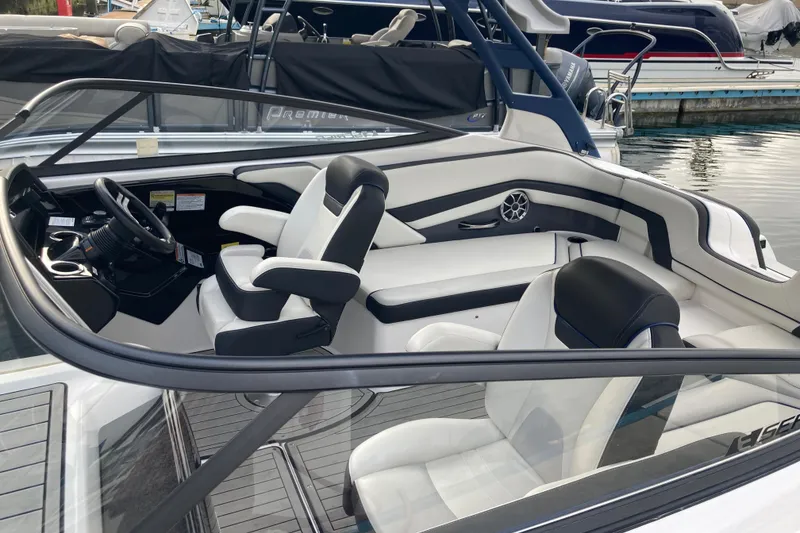 Slide: The Image of 2020 Yamaha Boats AR242SE interior with sleek seating and modern dashboard at a marina. - 6