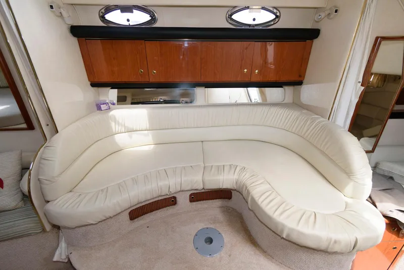 Slide: The Image of Interior of 2000 Sea Ray 340 Sundancer with curved white leather seating and wooden cabinets. - 12
