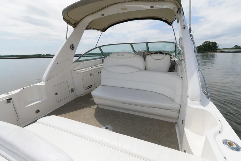 Slide: The Image of 2000 Sea Ray 340 Sundancer boat interior with white seating and canopy on calm water. - 5