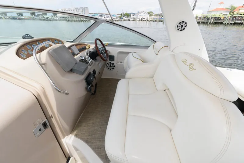 Slide: The Image of Cockpit of 2000 Sea Ray 340 Sundancer with white seating and steering wheel, dockside view. - 7