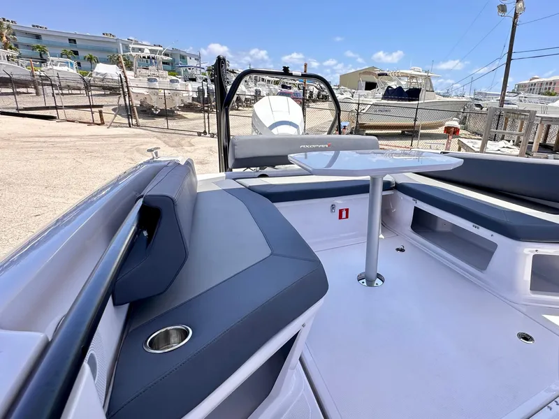 Slide: The Image of 2022 Axopar 22 T-Top boat interior with seating and table, docked at marina. - 11
