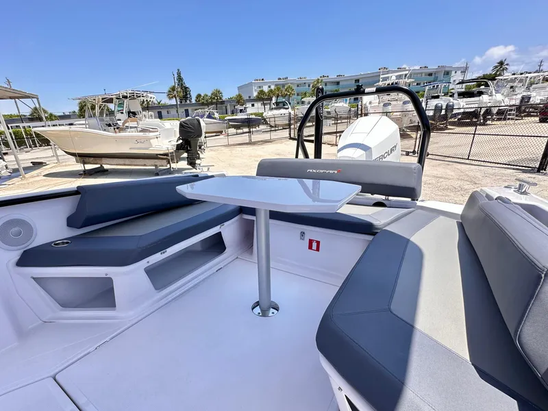 Slide: The Image of 2022 Axopar 22 T-Top boat interior with seating and table, docked in a marina. - 14