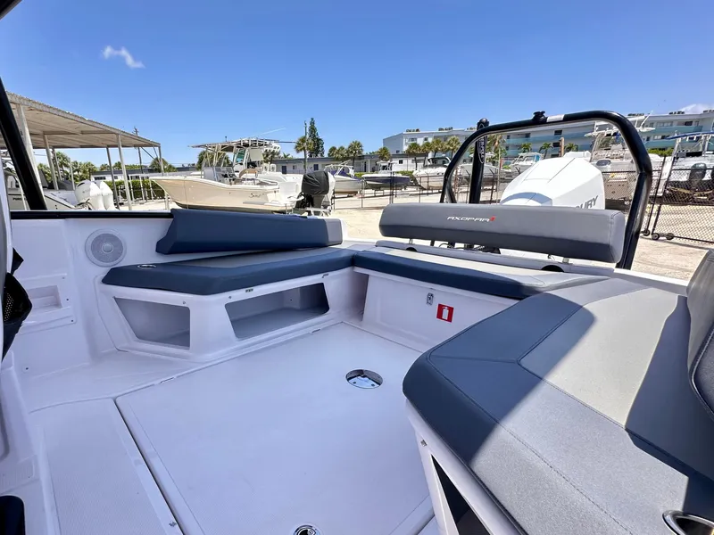Slide: The Image of 2022 Axopar 22 T-Top boat interior with seating, docked under clear blue sky. - 15