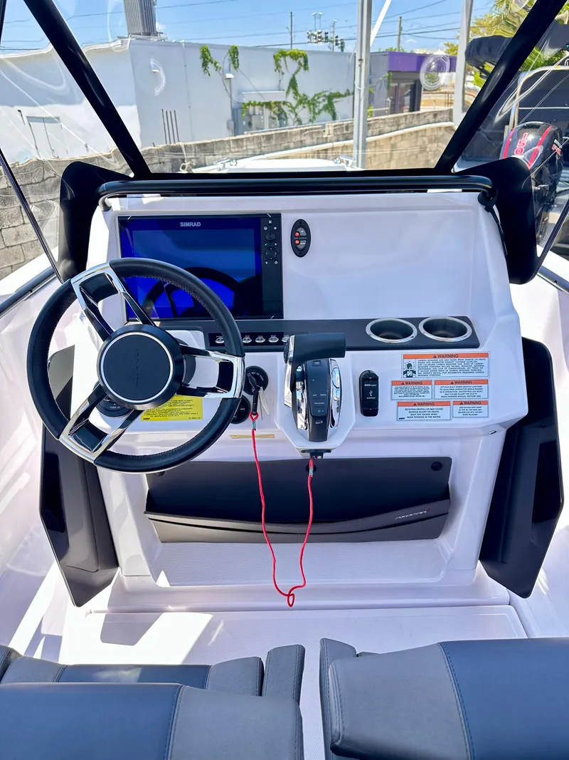 Slide: The Image of 2022 Axopar 22 T-Top boat dashboard with steering wheel, controls, and navigation screen. - 19