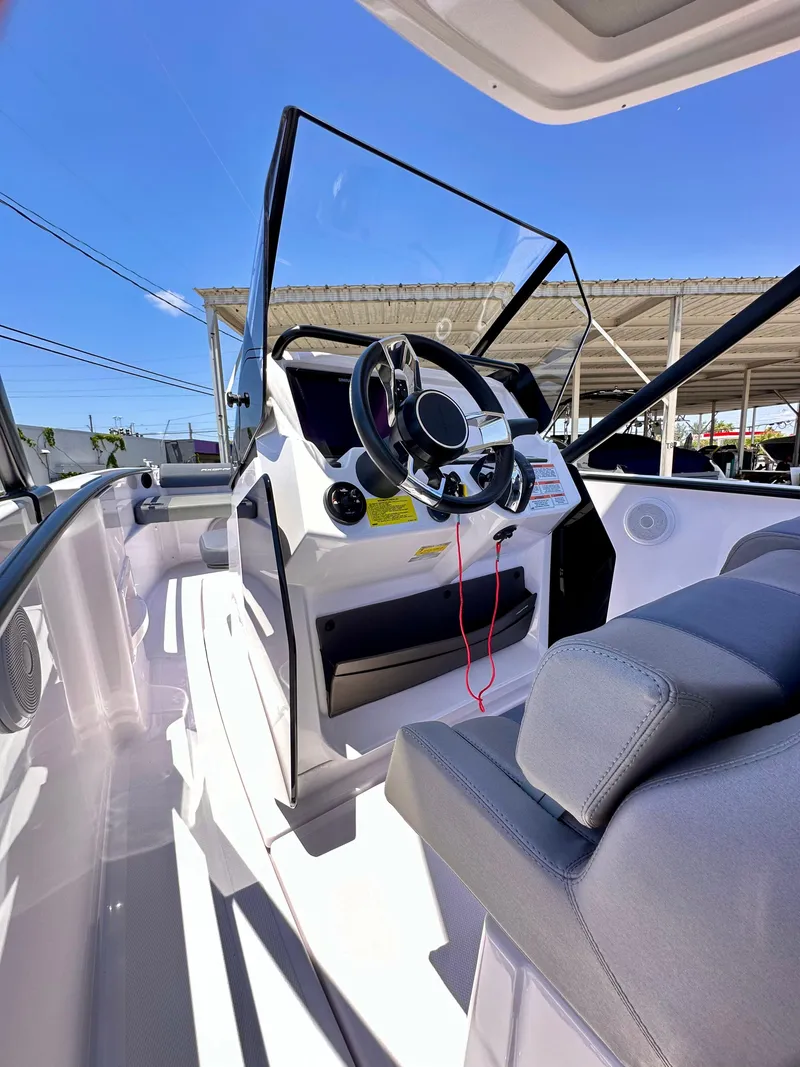 Slide: The Image of 2022 Axopar 22 T-Top boat interior with steering wheel and seating, under clear blue sky. - 20