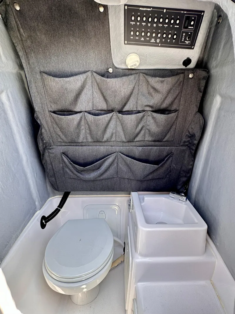 Slide: The Image of 2022 Axopar 22 T-Top interior with toilet, sink, and storage compartments. - 27