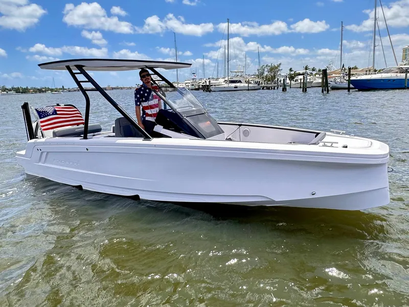Slide: The Image of 2022 Axopar 22 T-Top boat on water, American flag, sunny day, marina background. - 28