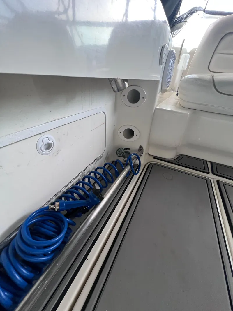 Slide: The Image of 2000 Sea Ray 290 Amberjack boat interior with coiled blue hose and storage compartment. - 10