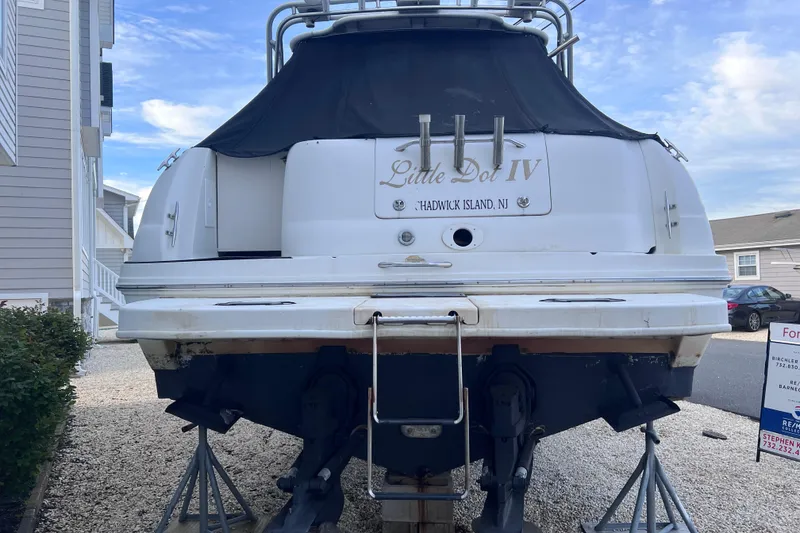 Slide: The Image of 2000 Sea Ray 290 Amberjack boat on stands, rear view, outdoor setting. - 3