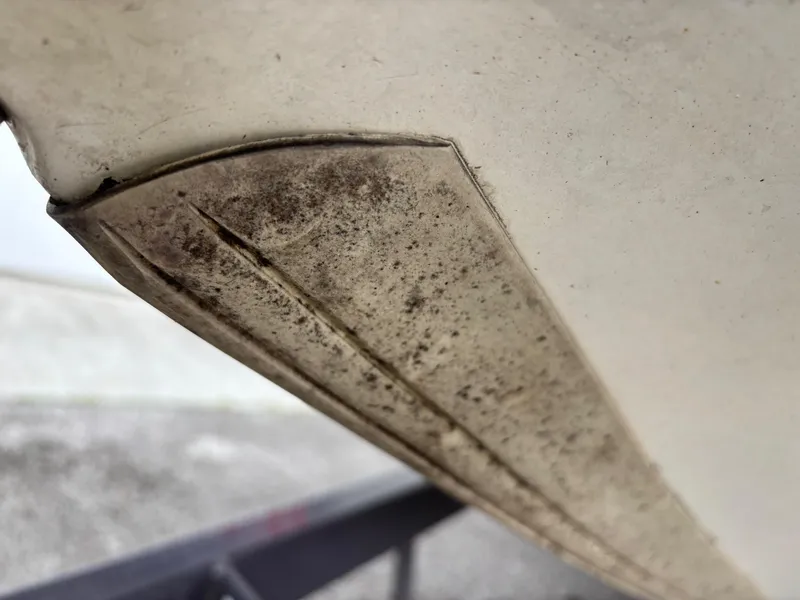Slide: The Image of Close-up of a 1999 Triton TR19 boat hull with visible wear and dirt. - 5