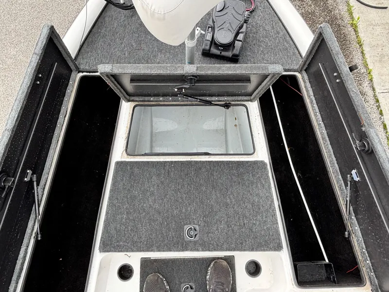 Slide: The Image of 1999 Triton TR19 boat interior with open storage compartments and gray carpeting. - 7