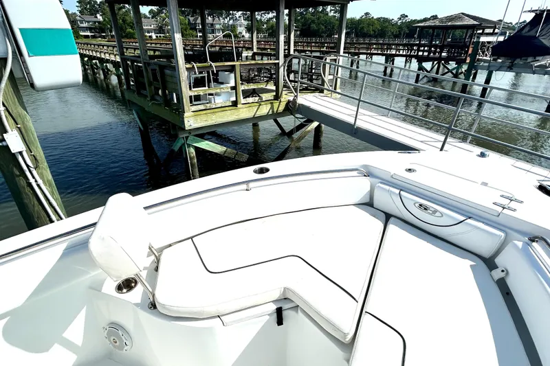 Slide: The Image of 2017 Sea Hunt Ultra 235 SE boat with white seating, docked near a wooden pier. - 13
